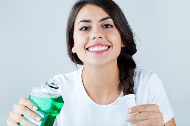 woman using mouthwash