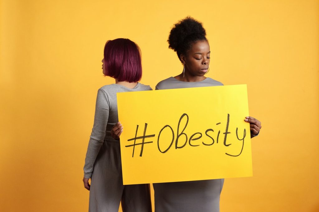 2 women holding sign #obesity