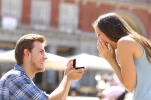 Young man proposing to his girlfriend in public.